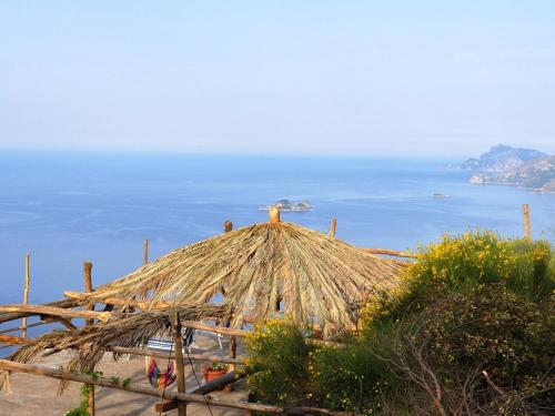 a straw hut with the ocean in the background at Holiday Home Path of the Gods by Interhome in Pianillo