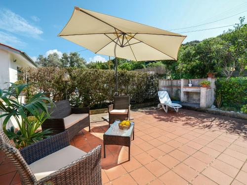 um pátio com um guarda-sol, uma mesa e cadeiras em Apartment Salita Bellavista by Interhome em Cavo
