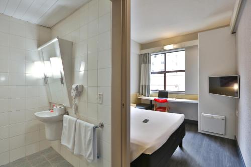 a bathroom with a tub and a toilet and a sink at Ibis Maringa in Maringá