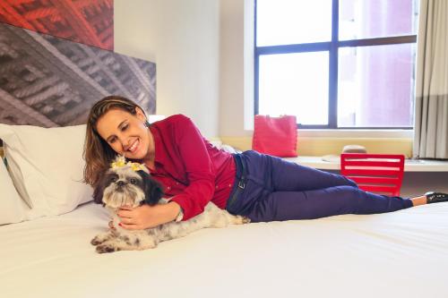 a woman laying on a bed with a dog at Ibis Maringa in Maringá