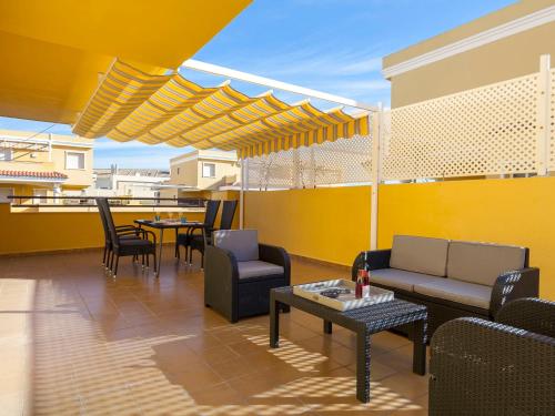 un patio con sillas, mesas y una pared amarilla en Apartment Cascadas de la Marina-2 by Interhome, en Denia