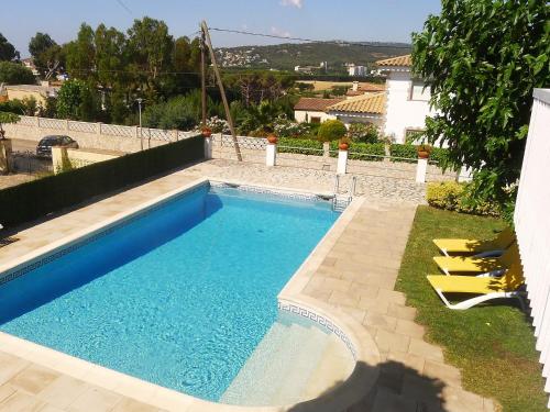 a swimming pool with two yellow chairs next to a house at Holiday Home Eva by Interhome in Sant Antoni de Calonge