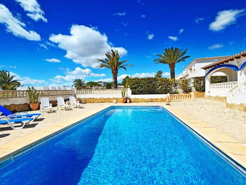 a swimming pool with chairs and palm trees at Holiday Home La Sabatera by Interhome in Moraira