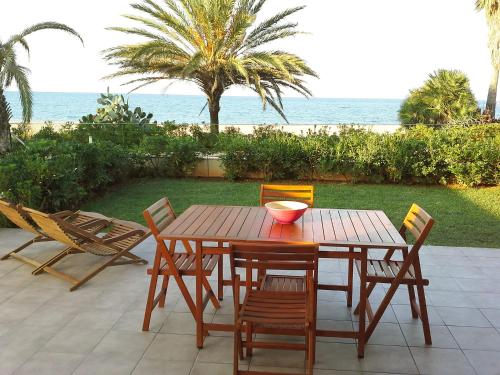 a wooden table and chairs with a view of the ocean at Apartment Marenia by Interhome in Denia