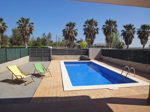 a swimming pool with two chairs next to a fence at Holiday Home Peiro by Interhome in L'Ampolla