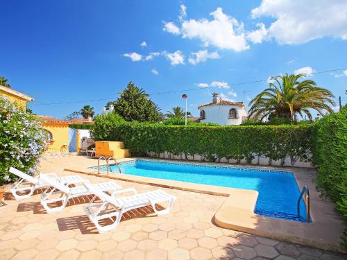 a swimming pool with lounge chairs next to a house at Villa Les Canyes by Interhome in Denia