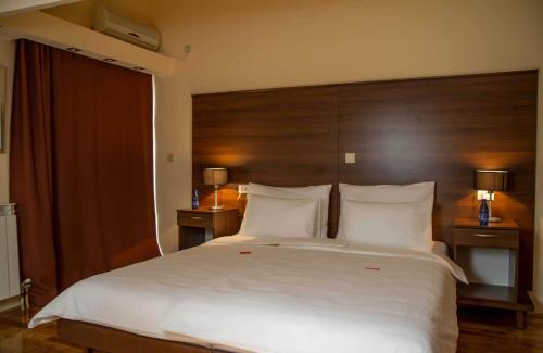 a bedroom with a large white bed with a wooden headboard at Hotel M in Podgorica