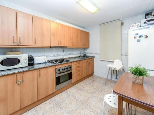 a kitchen with wooden cabinets and a table and a refrigerator at Apartment Camp Nou- Travessera de les Corts by Interhome in Barcelona