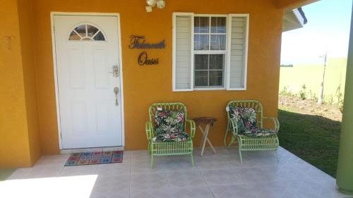 a porch with two chairs and a white door at Falmouth Oasis in Florence Hall
