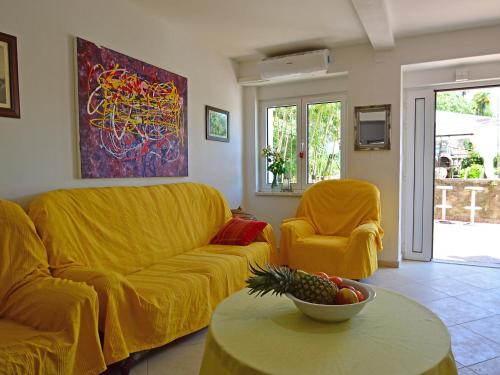 a living room with yellow furniture and a bowl of fruit on a table at Apartment Andrea by Interhome in Opatija