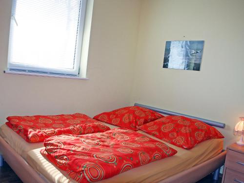 two red pillows on a bed in a bedroom at Holiday Home Goetheallee by Interhome in Krakow am See