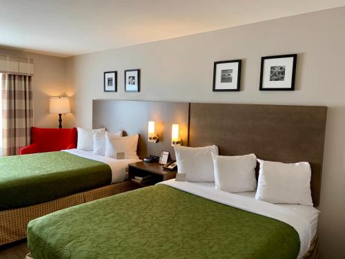 Country Inn & Suites by Radisson Kenosha - Pleasant Prairie في كينوشا: غرفة فندقية بسريرين وكرسي احمر