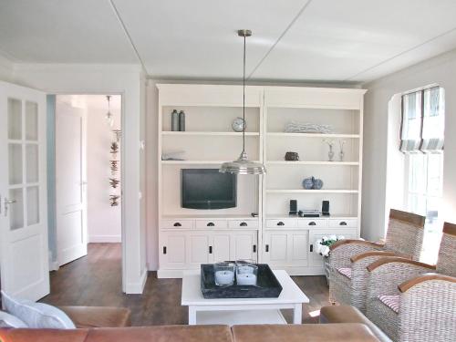 ein Wohnzimmer mit einem TV und einem Sofa in der Unterkunft Holiday Home Wiringherlant-7 by Interhome in Noordstroe