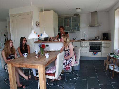eine Gruppe von Frauen, die in einer Küche am Tisch sitzen in der Unterkunft Holiday Home Wiringherlant-2 by Interhome in Noordstroe