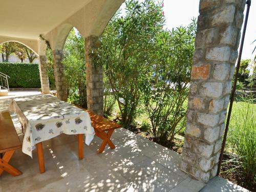 a table and chairs on a patio with a stone wall at Holiday Home Jelka by Interhome in Njivice