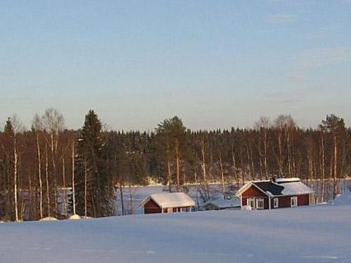 twee gebouwen in een sneeuwveld bij Holiday Home Talvikki by Interhome in Kurkimaki