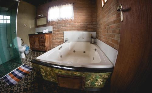 uma grande banheira na casa de banho com uma parede de tijolos em Chalés Belvedere em Conceição do Ibitipoca