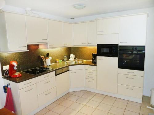 een keuken met witte kasten en een zwart apparaat bij Holiday Home Bosrijk Ruighenrode-1 by Interhome in Lochem