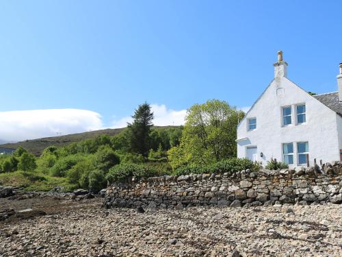 a white house with a stone wall in front at Holiday Home Dunan by Interhome in Dunan