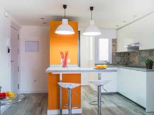 una cocina naranja y blanca con barra y taburetes en Apartment Estrella del mar by Interhome, en Rincón de la Victoria