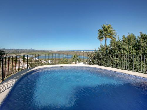 a large blue swimming pool with a fence and palm trees at Villa Villa Flores by Interhome in Monte Pego