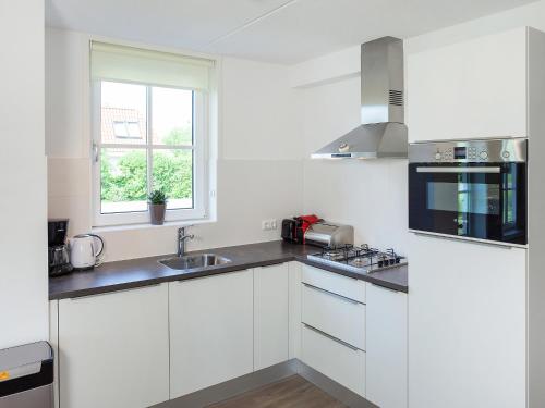 a kitchen with white cabinets and a sink and a window at Holiday Home Alk 6 by Interhome in Noordwijk
