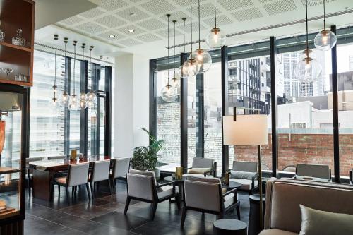 a dining room with a table and chairs and large windows at Novotel Melbourne Central in Melbourne
