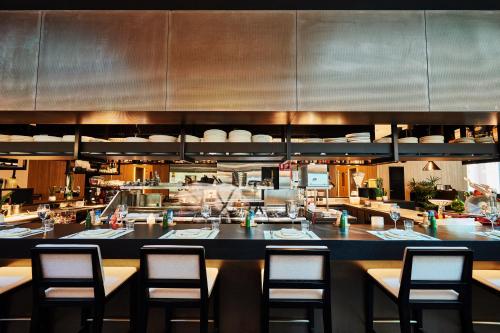 a restaurant with a bar with chairs and a kitchen at ibis Melbourne Central in Melbourne