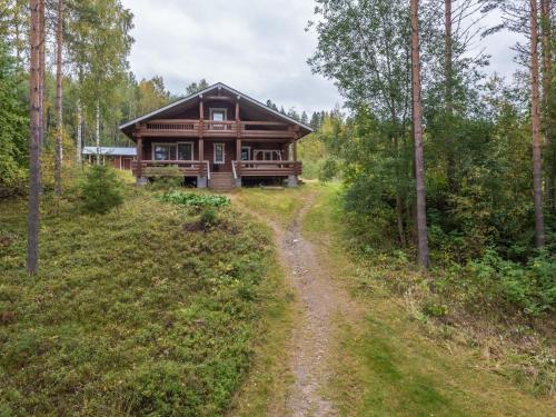 uma cabana de madeira na floresta com uma estrada de terra em frente em Holiday Home Mäntyrinne by Interhome em Ruottila