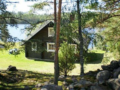 a house in the middle of a yard with trees at Holiday Home 6144 by Interhome in Jäniskylä