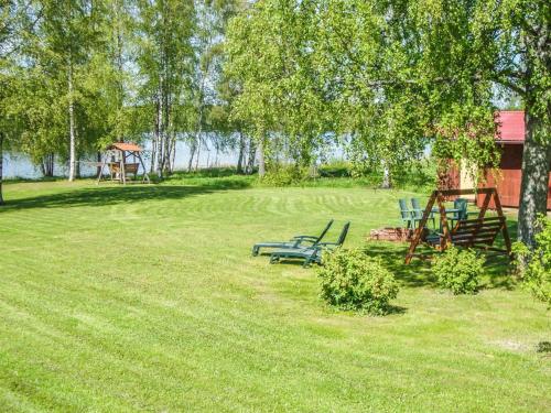 a park with two benches and a playground at Holiday Home Rantaheikari by Interhome in Torvoila