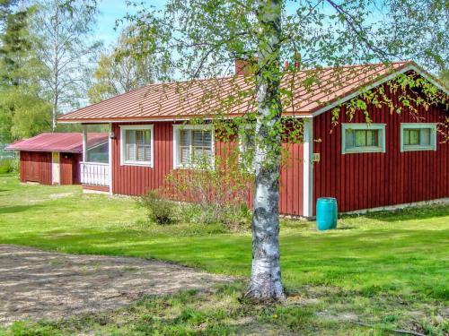 a red house with a tree in front of it at Holiday Home Rantaheikari by Interhome in Torvoila
