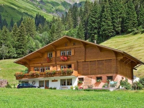 a large wooden house on a hill in a field at Apartment Abelied by Interhome in Adelboden
