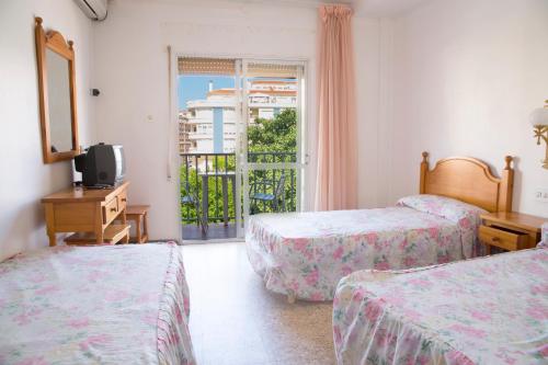 a room with two beds and a television and a window at Hostal Susi in Peniscola