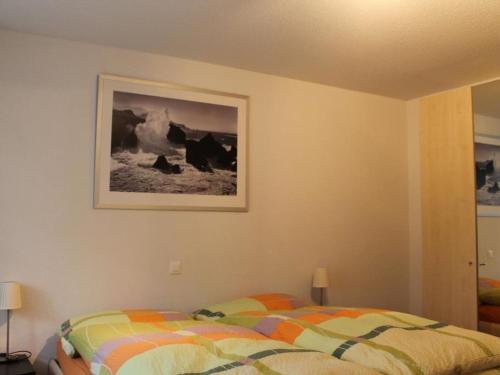 um quarto com uma cama e uma fotografia na parede em Apartment Rawilstrasse 33 by Interhome em Lenk