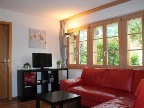 un soggiorno con divano rosso e TV di Apartment Rawilstrasse 33 by Interhome a Lenk