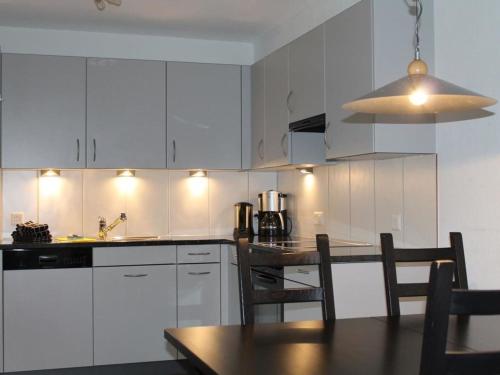 una cucina con armadi bianchi e tavolo con sedie di Apartment Rawilstrasse 33 by Interhome a Lenk