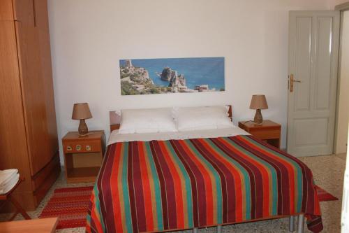 1 dormitorio con 1 cama con una manta a rayas de colores en Baglio Gammicchia B&B, en Erice