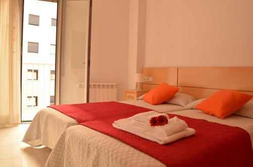 a bedroom with a bed with two towels and a flower on it at Apartamentos Navas in Barcelona