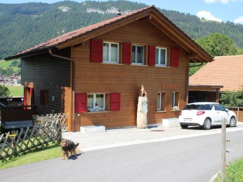 een vrouw die voor een houten huis staat bij Apartment Schön-Egg by Interhome in Zweisimmen