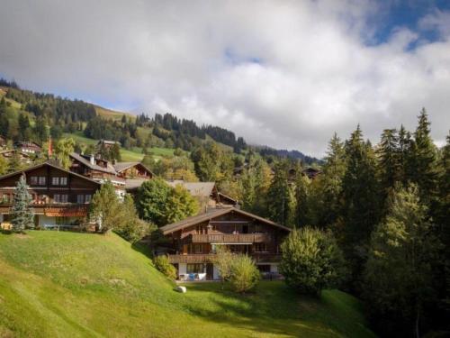 eine Gruppe von Häusern auf einem grünen Hügel mit Bäumen in der Unterkunft Apartment Graebi by Interhome in Gstaad