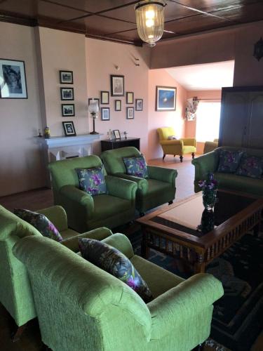 a living room with green couches and a table at Tree of Life Grand Oak Manor Binsar in Binsar