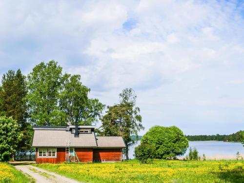a small red house in a field next to a lake at Holiday Home Ettone by Interhome in Lipinlahti