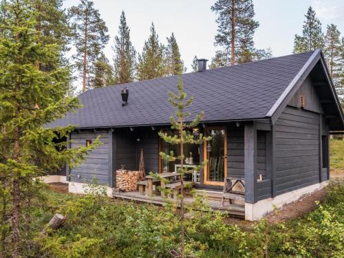 a black cabin with a porch in the woods at Holiday Home Neljä vuodenaikaa a1-karpalo by Interhome in Ylläsjärvi