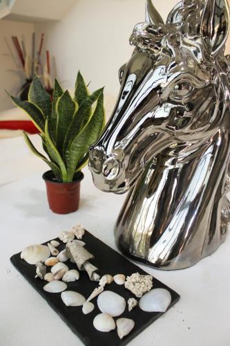 a table with a silver horse and a plate of shells at Show Pony Beach Resort and Suites in Las Lajas