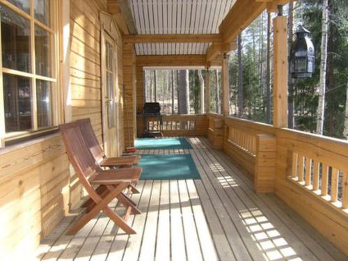 a porch of a wooden cabin with a rocking chair at Holiday Home Mustikka by Interhome in Röylä