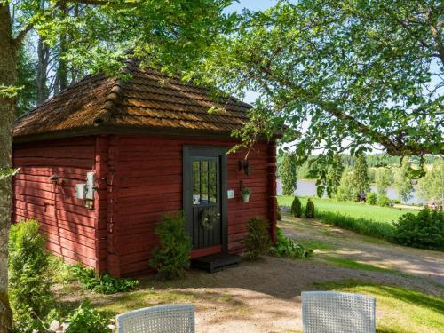 a small red building with two chairs in a yard at Holiday Home Isopehtoori by Interhome in Hirsjärvi