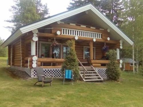 a log cabin with a porch and chairs in the yard at Holiday Home Suviranta by Interhome in Syvärinpää