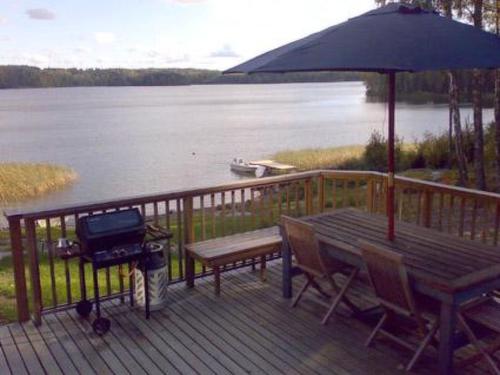 um deque com comodidades para churrascos, uma mesa de piquenique e um guarda-chuva em Holiday Home Karri by Interhome em Tallnäs