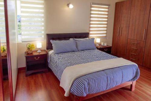 a bedroom with a bed with blue and white stripes at Hotel Casa Sayu in Tumbaco